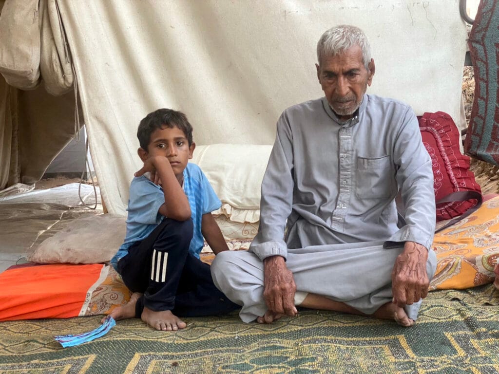 Abdullah Abu Jalilah, de 82 años, con su nieto Adam, de 6, en una tienda de campaña improvisada en el barrio de Al-Saraya, en el centro de la ciudad de Gaza, el 18 de julio de 2025.