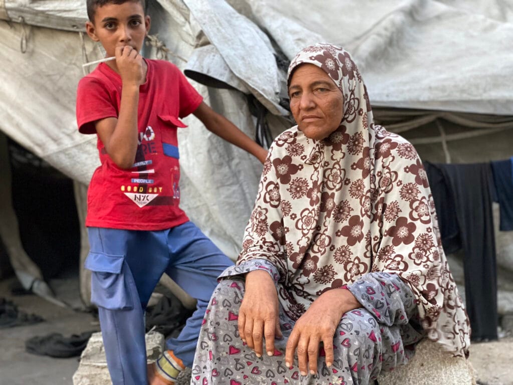 Sara Marouf, de 53 años, con su nieto frente a su tienda de campaña en la calle Omar Al-Mukhtar, en el centro de la ciudad de Gaza, el 18 de julio de 2025.