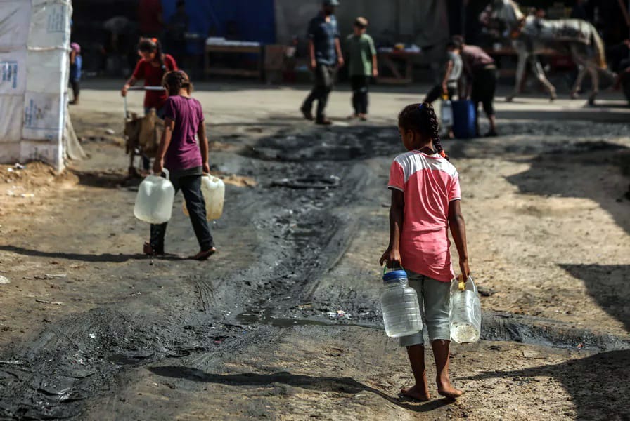 Niños palestinos desplazados llevan recipientes para llenarlos de agua en un campo de desplazados improvisado en Deir el-Balah, en el centro de la Franja de Gaza.